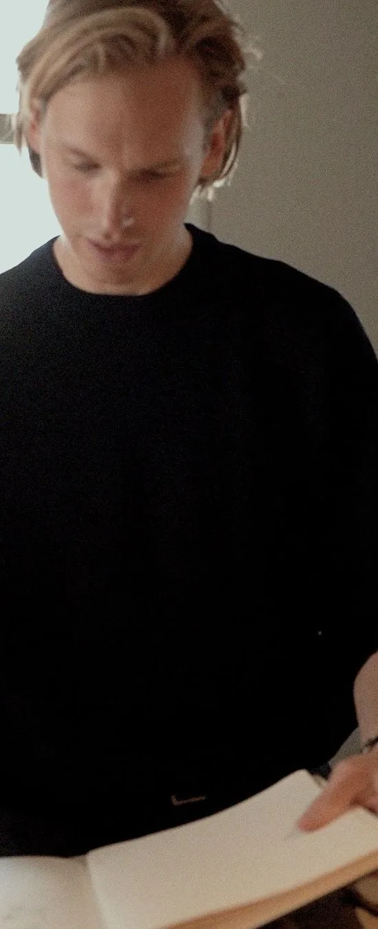 Maurits looking down at an open notebook.