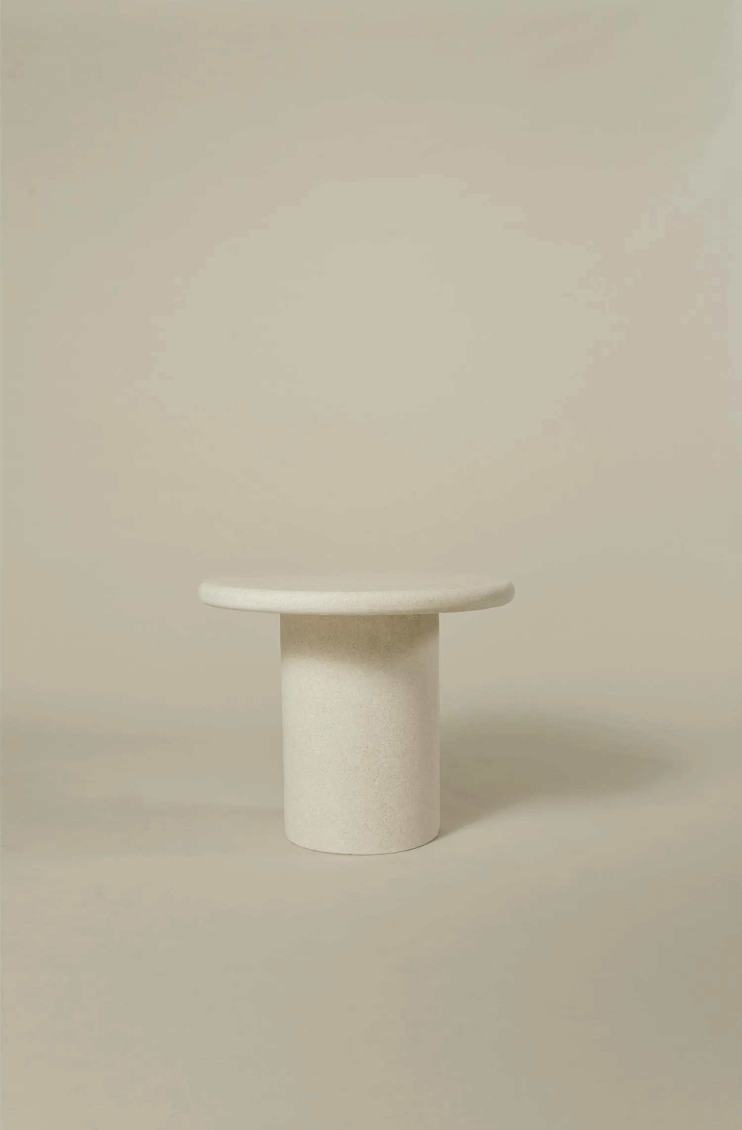 Small round Mushroom Durastone coffee table with cylindrical base, shown against a neutral background.
