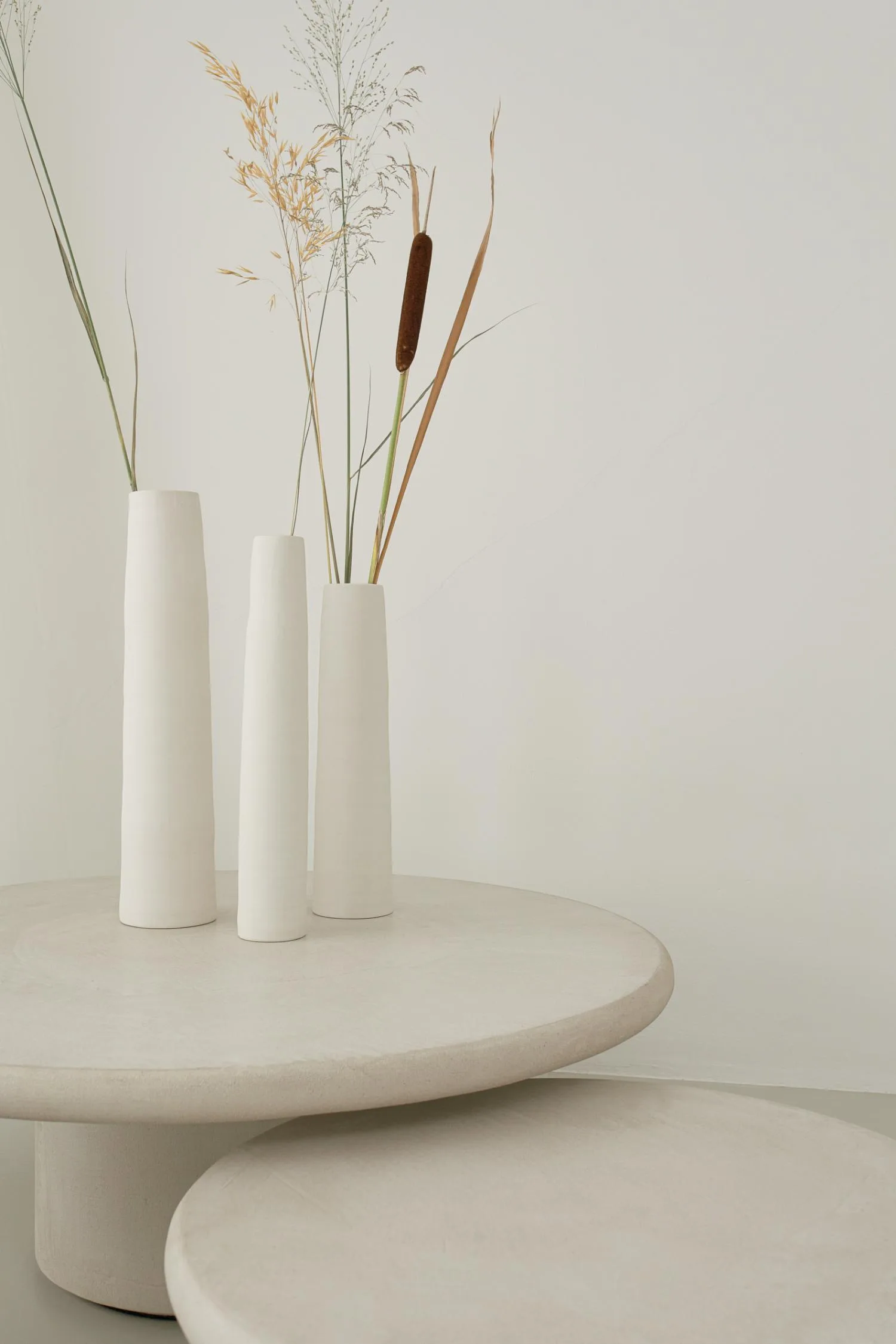 Detail of textured Mushroom Stucco coffee tabletop with tall ceramic vases holding dried stems.