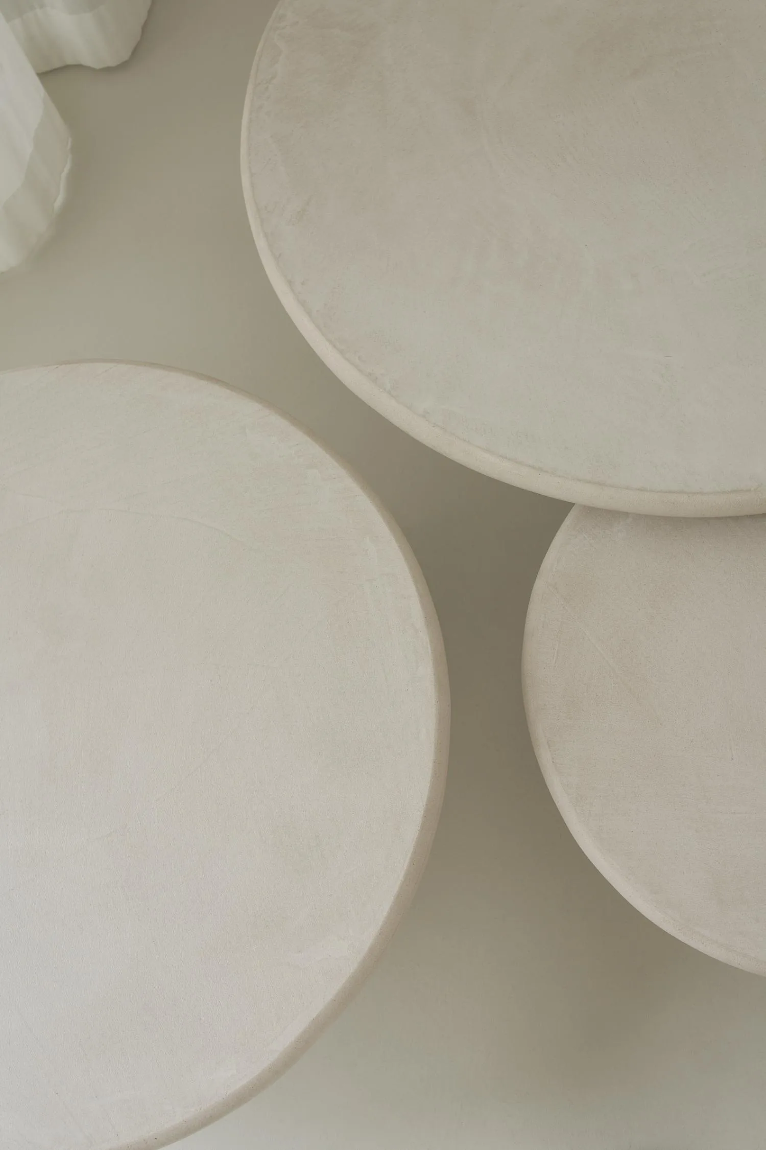 Top view of three round Mushroom Stucco coffee tables in soft-toned plaster finish.