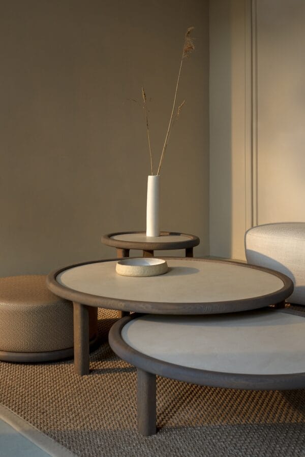 Top view of Amalfi Coffee Tables with round beige tops and dark wooden edges, styled with ceramic accessories on a woven rug.