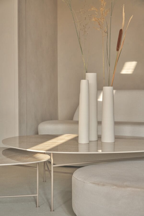 Como Coffee Table Set with light metal frame and glossy stone-look tops, styled with tall ceramic vases in a soft-toned interior.