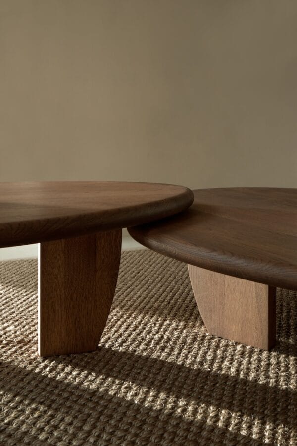 Close-up of two Como Coffee Tables in oak, showing rounded tabletops and sculptural legs on a woven rug.