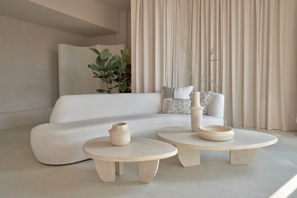 Como Coffee Table Set in stucco finish styled in a minimal living room with a curved white sofa, neutral curtains, and decorative ceramics.
