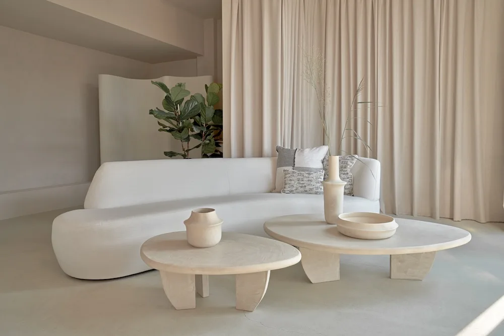 Como Coffee Table Set in stucco finish styled in a minimal living room with a curved white sofa, neutral curtains, and decorative ceramics.