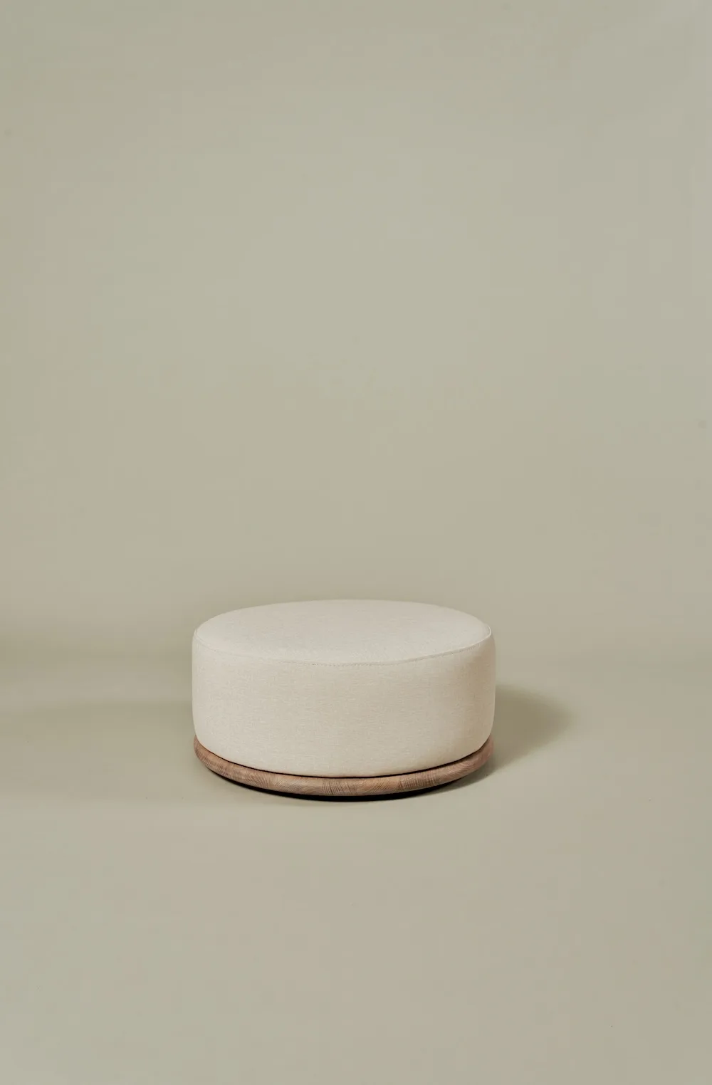 Miller Coffee Table Set pouf with round beige upholstery and wooden base.