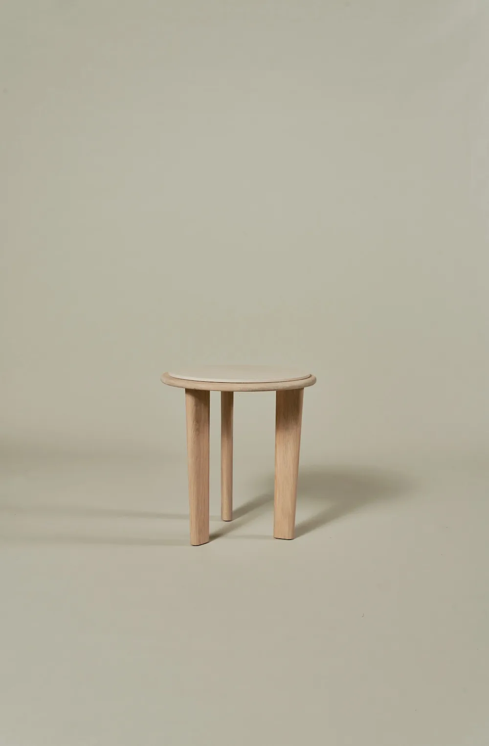 Small Miller Coffee Table with round travertine top and three light wooden legs."