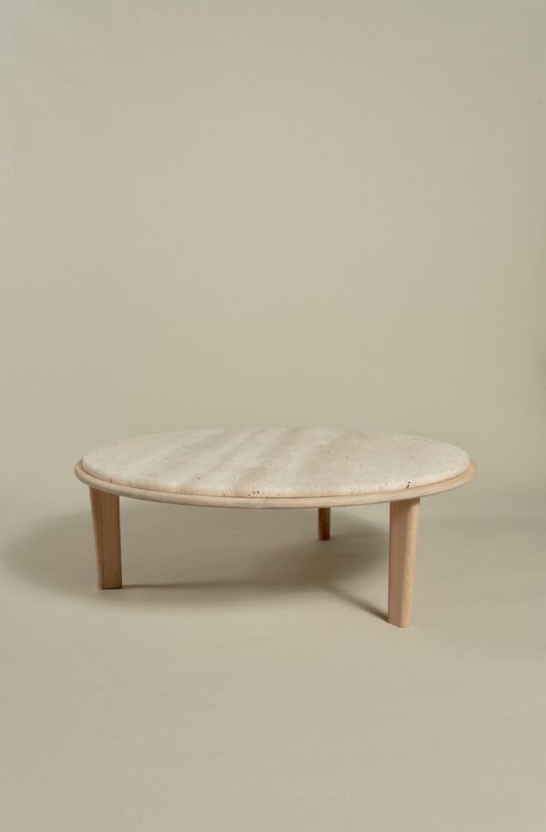 Miller Coffee Table with round travertine top and light wooden legs.